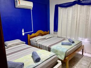 two beds in a room with blue walls at Pousada das Águas in Piratuba