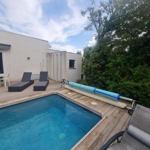 a swimming pool on a wooden deck next to a house at Villa d'architecte Uzes in Sainte Anastasie - Aubarne