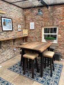 a wooden table and chairs in front of a brick wall at Newsham Grange Farm in Thirsk