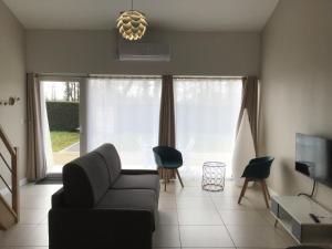 sala de estar con sofá y TV en Clos du Béron- Appartement meublé de tourisme, en Cappelle-en-Pévèle
