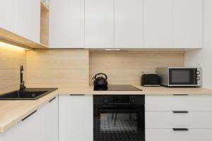 kuchnia z białymi szafkami i czarną kuchenką mikrofalową w obiekcie Spacious Apartment Suwalska Targówek by Renters w Warszawie