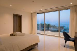 a bedroom with a bed and a desk and a large window at Love Bridge Seaview Villas in Ayia Napa +53 photos