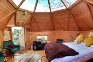 Praze an BeebleにあるRomantic Treehouse with Hot Tub & BBQ Lodgeの木製の部屋に大型ベッドが備わるベッドルーム1室が備わります。