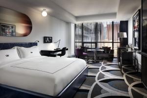 a hotel room with a white bed and a desk at Bisha Hotel Toronto in Toronto
