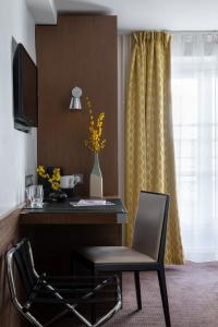 パリにあるホテル ル コリセーのデスク、椅子、テレビが備わる客室です。