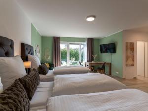 una camera d'albergo con tre letti e una televisione di GLEUEL INN - digital hotel & serviced apartments & boardinghouse mit voll ausgestatteten Küchen a Hürth