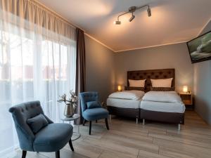 ein Schlafzimmer mit einem Bett und zwei blauen Stühlen in der Unterkunft GLEUEL INN - digital hotel & serviced apartments & boardinghouse mit voll ausgestatteten Küchen in Hürth