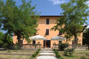 a building with trees and umbrellas in front of it at Villa Boldrini b&b in Venturina Terme