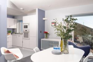 une cuisine et une salle à manger avec une table blanche et des fleurs dans l'établissement Blue Yonder, Praa Sands, à Praa Sands