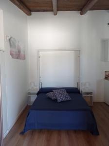 1 dormitorio con 1 cama azul y paredes blancas en La Casetta, en Santa Croce Camerina