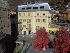 un bâtiment jaune avec des arbres rouges devant lui dans l'établissement Hotel Alla Posta, à Saint-Vincent