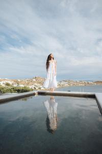 een vrouw in een witte jurk die in een plas water staat bij Noima Boutique Hotel Mykonos in Agios Ioannis Mykonos