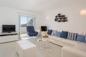 a white living room with a couch and a tv at Beautiful apartment set in the heart of Quinta in Almancil