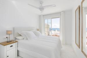 a white bedroom with a white bed and a window at Mirador de la Marina in La Herradura