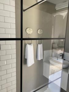 a glass shower door with white towels in a bathroom at The Stables on Drew Avenue in Howick