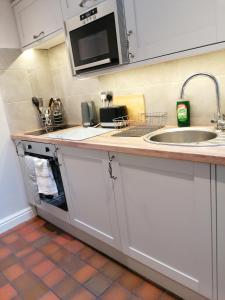 encimera de cocina con fregadero y microondas en Halt Cottage, en Bridgnorth