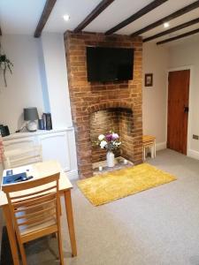 a living room with a brick fireplace with a flat screen tv at Halt Cottage in Bridgnorth