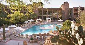 a swimming pool with chairs and umbrellas and a building at Loews Ventana Canyon Resort in Tucson