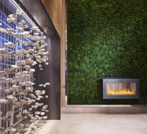 een open haard in een lobby met een muur met schelpen bij Loews Chicago O'Hare Hotel in Rosemont