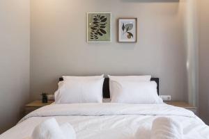 a bedroom with a bed with white sheets and pillows at Piraeus Deluxe 2BDR Apt - near metro and port in Piraeus