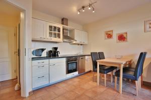 una cucina con armadi bianchi, tavolo e sedie di Sunshine-Residenz Sunshine Residenz Appartement 2 a Timmendorfer Strand