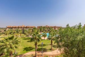Escale de Charme - Prestigia Golf - Vue piscine في مراكش: حديقة فيها نخيل ومنتجع