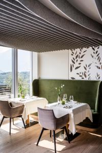 a dining room with two tables and a green bench at Hotel Mitterplatt (Schenna Resort) in Schenna
