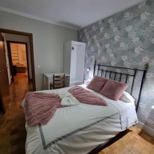 sypialnia z dużym łóżkiem z różowymi poduszkami w obiekcie Apartamentos Paz Ribadeo w mieście Ribadeo