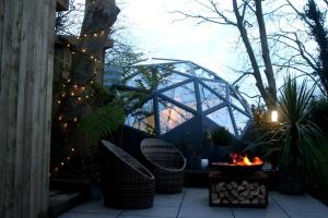 a patio with chairs and a fire pit with lights at Romance - Stargazing - Hot tub & sauna! in Camborne