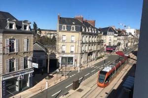 un autobús rojo conduciendo por una calle de la ciudad con edificios en Le Loge'Mans, en Le Mans