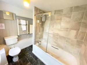 a bathroom with a toilet and a tub and a shower at Catcune Superior Suite in Gorebridge