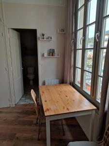 een eetkamer met een houten tafel en een aantal ramen bij Appartement au bord du lac in Bagnoles de l'Orne