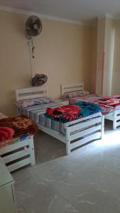 een kamer met 3 bedden en een ventilator bij Sweet Home- No Egyptian in Hurghada