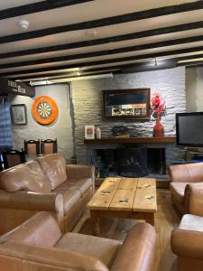a living room with leather furniture and a fireplace at The Pickwick Inn in Kingsbridge