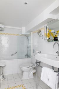 bagno bianco con servizi igienici e lavandino di Hôtel Le Colisée a Parigi