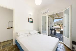 a white bedroom with a bed and a balcony at A Delight House in Maráthion