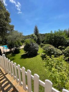 una valla blanca junto a un patio con árboles y arbustos en Le Clos Serein, en Le Beausset