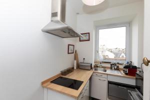 una pequeña cocina con fregadero y ventana en La Grève du Portrieux, en Saint-Quay-Portrieux
