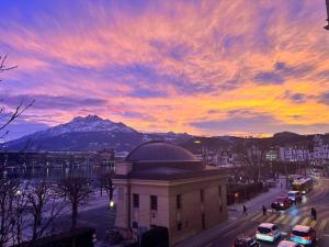 a sunset over a city with a building and a mountain at Belle Epoque Luzern in Lucerne