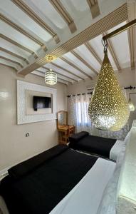 - un salon avec un grand lit et un lustre dans l'établissement Hôtel Zaghro, à Ouarzazate