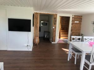 a living room with a flat screen tv on a wall at Mysig lantlig stuga, Nycklarör in Korsberga