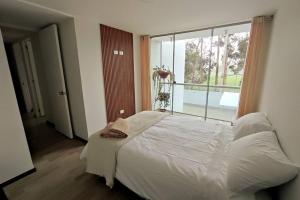 a bedroom with a white bed and a large window at Departamento de Isa in Cajamarca