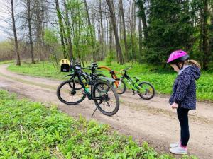 uma menina ao lado de duas bicicletas numa estrada de terra batida em Anielski Zakątek em Kolonia Rybacka