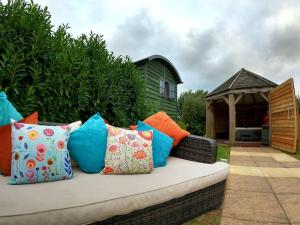 a couch with colorful pillows sitting in a yard at Romantic Retreat - Luxury Shepherds Hut + Hot Tub! in Camborne