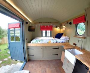 a caravan with a kitchen and a bed in it at Romantic Retreat - Luxury Shepherds Hut + Hot Tub! in Camborne