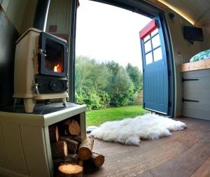 an open door of a camping tent with a stove at Romantic Retreat - Luxury Shepherds Hut + Hot Tub! in Camborne