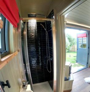 a bathroom with a shower with a glass door at Romantic Retreat - Luxury Shepherds Hut + Hot Tub! in Camborne