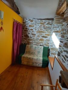 a room with a couch in a room with a stone wall at Petite bergerie en pierres tout confort in Salles-Curan