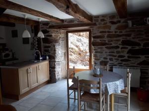 a kitchen with a table with chairs and a window at Petite bergerie en pierres tout confort in Salles-Curan
