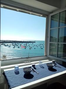 a table in a window with boats in the water at La Grève du Portrieux in Saint-Quay-Portrieux